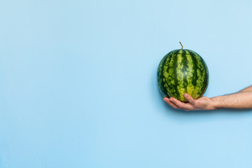 Man's hand holding a watermelon