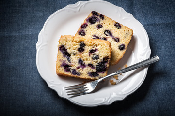 Two slices of Blueberry Tea Bread on a plate with fork and blue background.