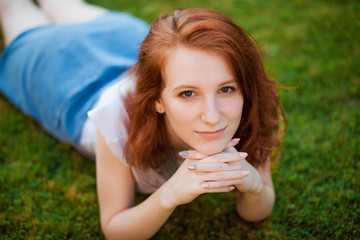 Red-haired girl lying on the lawn in the Park