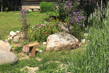 Garden with flowerbed, stones and rye on sunny day