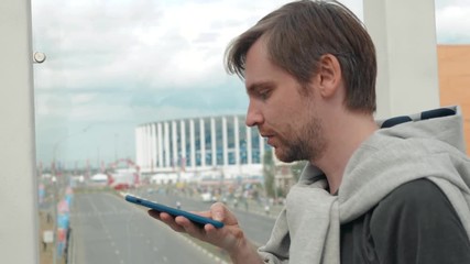 Handsome stylish man student freelancer leaving message using voice recognition, speaking at smartphone on street. Helper find stadium background - Powered by Adobe