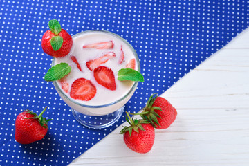 Homemade yogurt with fresh red strawberry on a wooden background. Top view.
