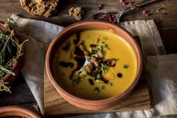 Pumpkin cream soup with cream and onion on dark wooden background top view, copy space.