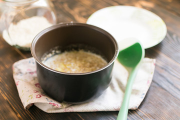 Oatmeal porridge cooked on milk in a saucepan on a dark wooden background.