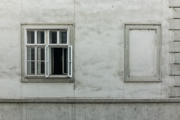 Fassade mit einem mehrteiligen, geöffneten und einem zugemauerten Fenster