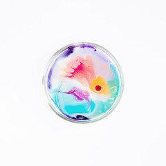 Fluid art in a petri dish. Colorful acrylic, ink, oil and watercolor marble paint splashes. Abstract fluid ocean of color or alien planet of liquid color.  Living colorful bacteria in a petri dish.