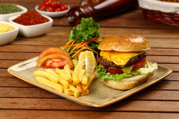 Tasty Cheeseburger and french fries on wood plate