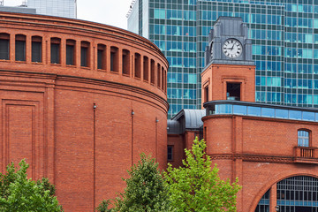 Buildings of Stary Browar with a clock tower and facade of a modern office building 
in Poznan - obrazy, fototapety, plakaty