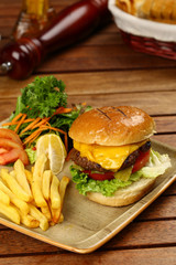 Tasty Cheeseburger and french fries on wood plate