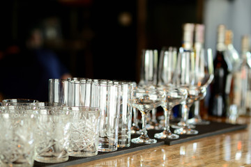 There are glasses on the bar counter which is in the restaurant