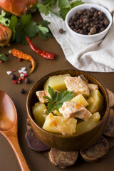 Potatoes stewed with chicken and vegetables in a wooden bowl.