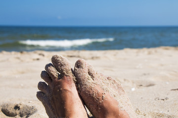 Close up of woman's feet on sandy beach with blue sea - relaxation, holidays