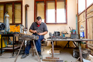 Artist is correcting figurine's posture with his bare hands