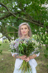 A young girl-florist comes up and makes a bouquet. Beautiful girl with a bouquet of flowers in the nature