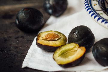 Fresh and ripe plums on a plate on a wooden background, macro, selective focus