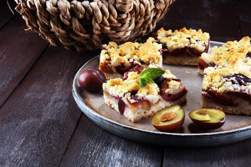 Rustic plum cake on wooden background with plums around.