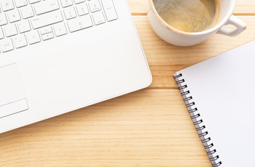 Teclado de un ordenador portátil blanco, cuaderno con espacio para texto y una taza de café. Flat-lay