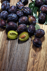 Plums on rustic background. Half of blue plum fruit. Many beautiful plums with leaves