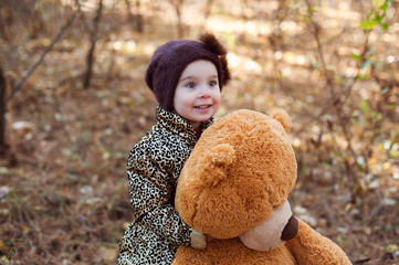 Little beautiful girl in autumn in park with toy