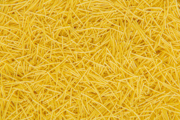 Close up of short and thin dry Italian vermicelli. Yellow raw or fresca wheat pasta background