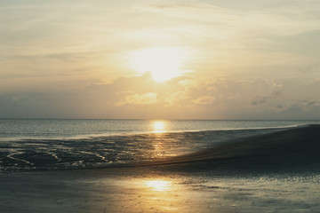 Sunrise over calm beach at low tide