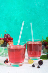 Berry compote. Fruit vitamin drink in glass and ripe fresh berries on a bright background. Vertical view