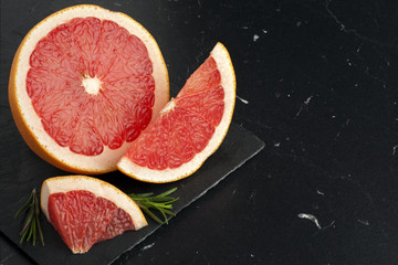 Juicy pieces of grapefruit on a black marble board