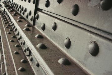 The metallic part is painted black. Huge screws firmly hold the massive parts of the bridge.