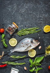 Raw fresh dorado with lemon on dark stone background. Top view