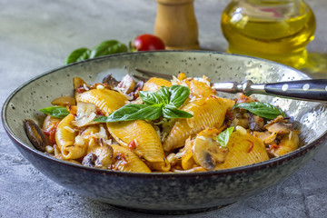 Pasta Conchiglioni with mushrooms in a vintage bowl on a dark stone or concrete background. Selective focus