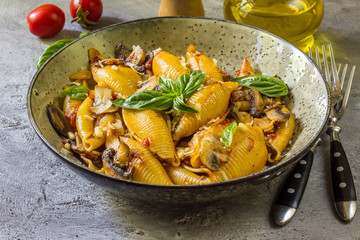 Pasta Conchiglioni with mushrooms in a vintage bowl on a dark stone or concrete background. Selective focus