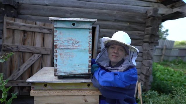 female beekeeper stands next to the hive. apiary in the summer, harvesting.
