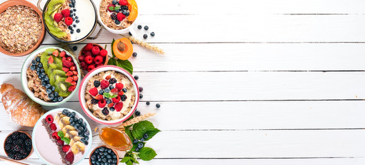 Large Assortment of porridge with fruit and berries. Breakfast. On a white wooden background. Top view. Free space for text.