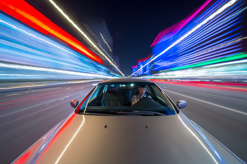 Fototapeta na wymiar Speed driving on car in night a city with neon glows and motion blured lights.