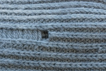 gray texture of woolen fabric with a hole