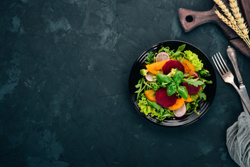 Salad of fresh beets, tomatoes, and lettuce. Healthy food. On the stone table. Top view. Free space for text.