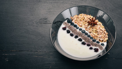Yogurt with oatmeal, and blueberries and blackberries. Chia seeds. Breakfast. On a wooden background. Top view. Free space for text.