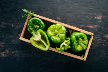 Fresh green pepper in a wooden box. Organic food. Top view. Free space for text.
