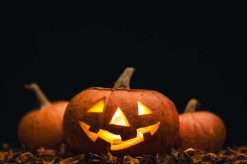Three magic Halloween pumpkins on a striped black-and-white table. Jack-o-lantern smiling face.