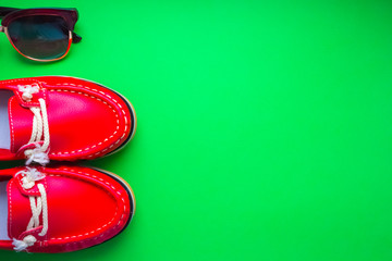 red moccasins with glasses on a green background