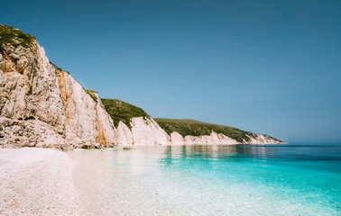 Fteri beach in Kefalonia Island, Greece. One of the most beautiful untouched pebble beach with pure azure emerald sea water surrounded by high white rocky cliffs of Kefalonia - obrazy, fototapety, plakaty