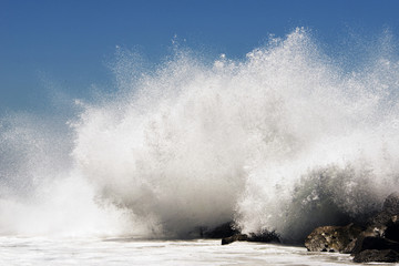 Fototapeta na wymiar An extreme high wave crashing to rocks in the beach of Venice, California in summertime
