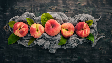 Flat peach with green leaves On a black wooden background. Top view. Free space for your text.