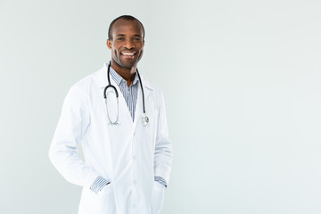 Joyful afro american doctor holding his hands in the pockets