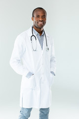 Smiling mature doctor standing against white background