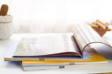 Opened magazine lying on the table, on the background of the window. 