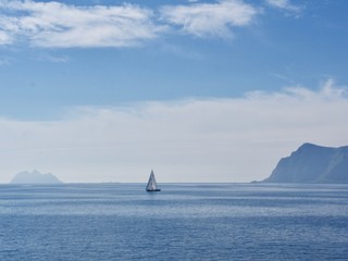 Saling boat at the berth in the Norwegian fjord on a background of blue sky and sea landscape