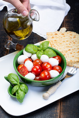 Italian soft cheese, young small balls mozzeralla cheese salad served with fresh basil, tasty ripe cherry tomatoes and Italian olive oil