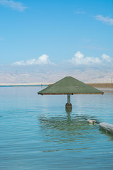 Wooden parasol on lowest salty lake in world below sea level Dead sea, near Ein Bokek, perfect place for medical treatments, climatotherapy, thalassotherapy and heliotherapy.