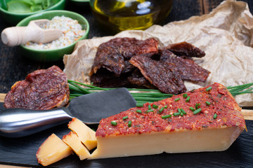 Piece of yellow hard cheese made with red sun dried tomatoes and herbs basil and chives